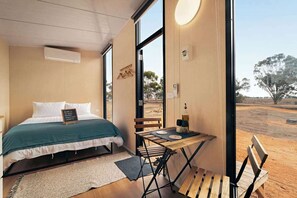 Een slaapkamer met een bed, een tafel met stoelen en uitzicht op het omliggende landschap.