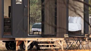 A modern, compact mobile home with a sleeping area, a small kitchenette, and a bathroom.