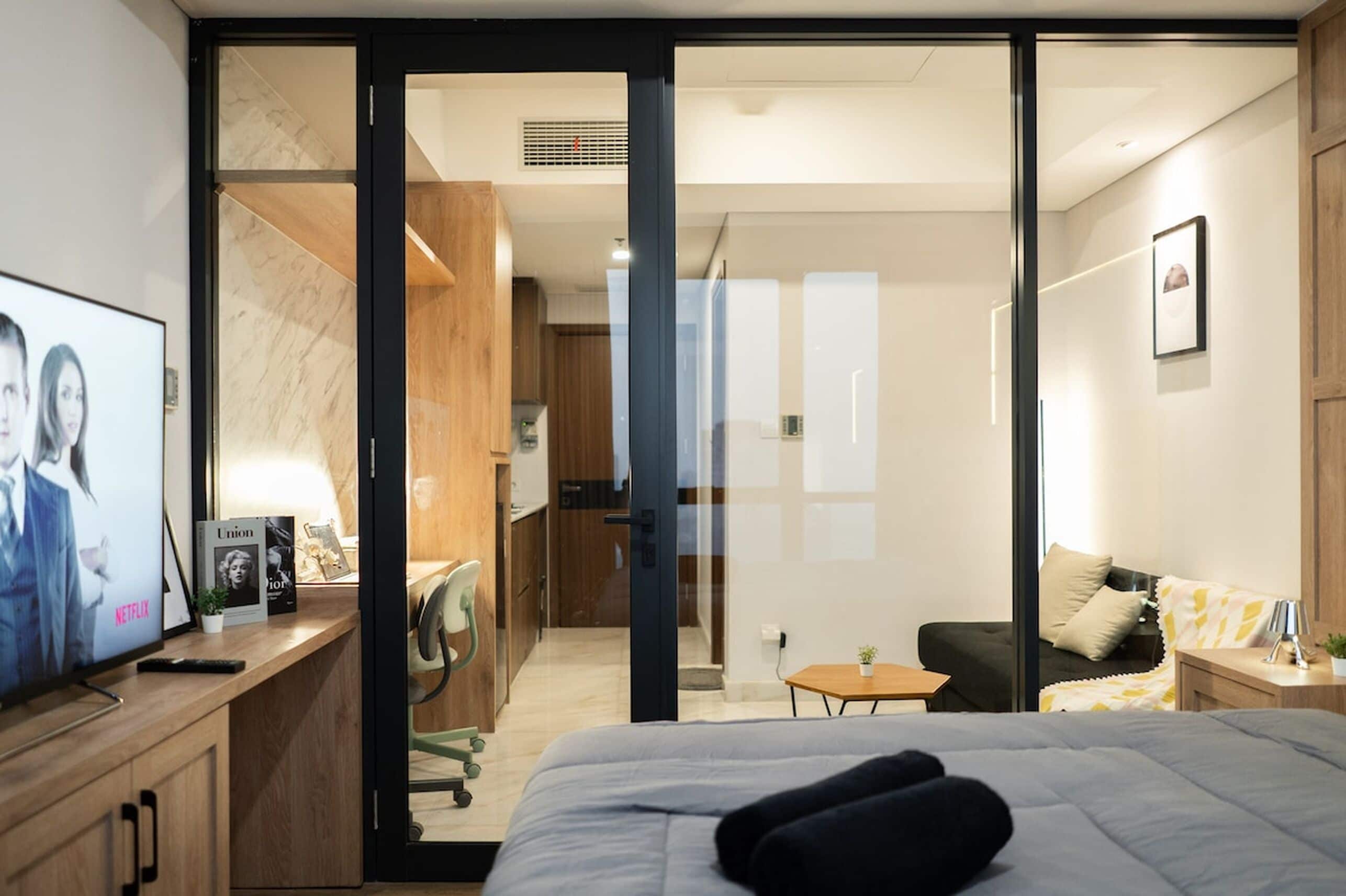Ett modernt hotellrum med en säng, ett skrivbord med en tv, ett litet bord och en soffa.