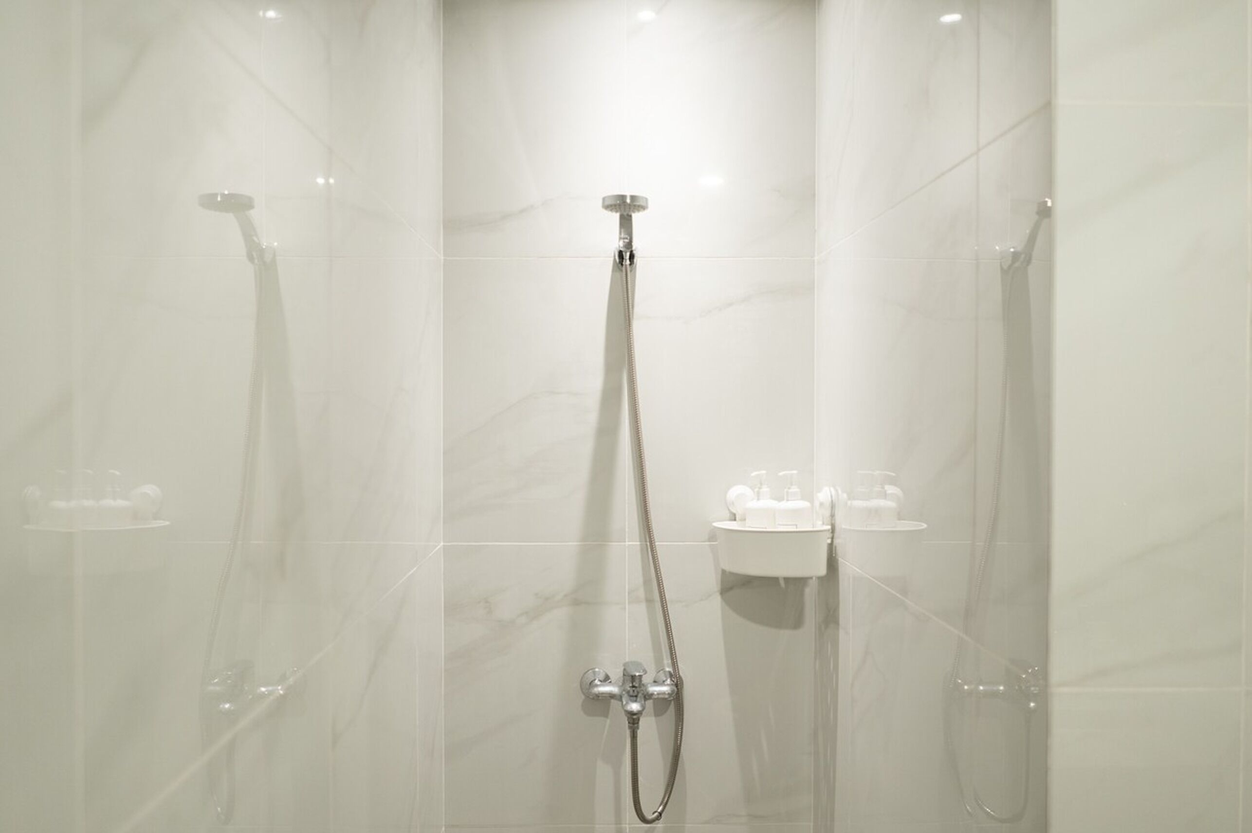 A modern shower area with a glass enclosure, a handheld showerhead, and a wall-mounted faucet.