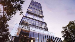 A modern skyscraper with reflective glass windows and a prominent sign at the base. - The Smith Luxury SkyView Apartments (Tangerang)