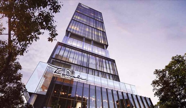 A modern skyscraper with reflective glass windows and a prominent sign at the base.