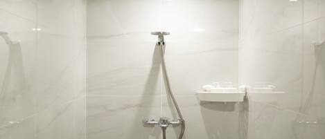 A modern shower with a handheld showerhead and a wall-mounted faucet.