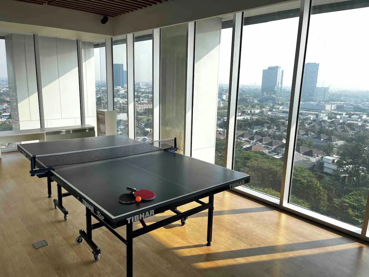 Una sala con ampie finestre affacciata su una vista urbana, con un tavolo da ping pong.