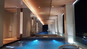 A modern indoor pool area with a wooden ceiling and a view of the night sky. - The Smith Luxury SkyView Apartments (Tangerang)