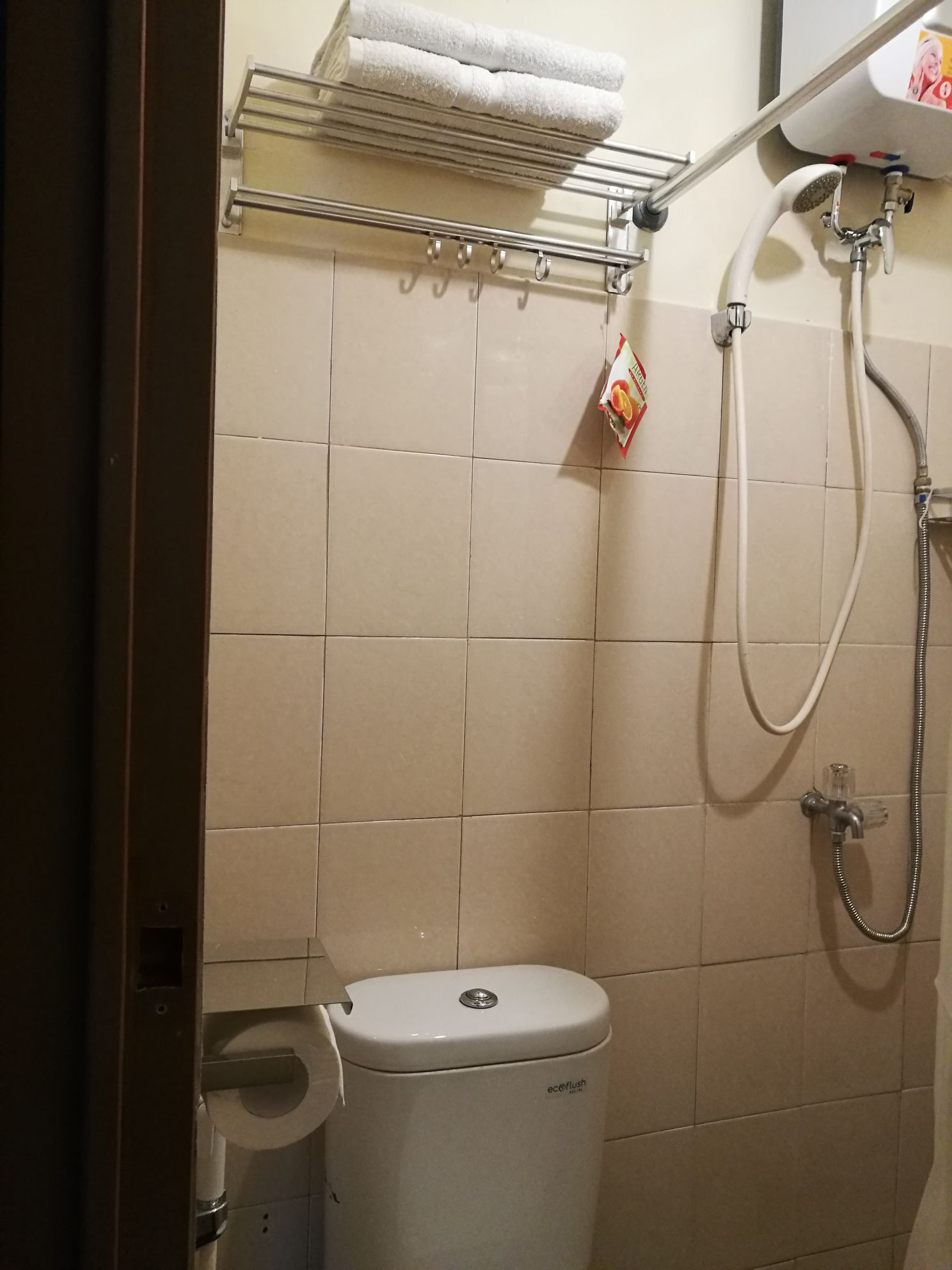 A bathroom with a toilet, a shower, and a towel rack with towels.