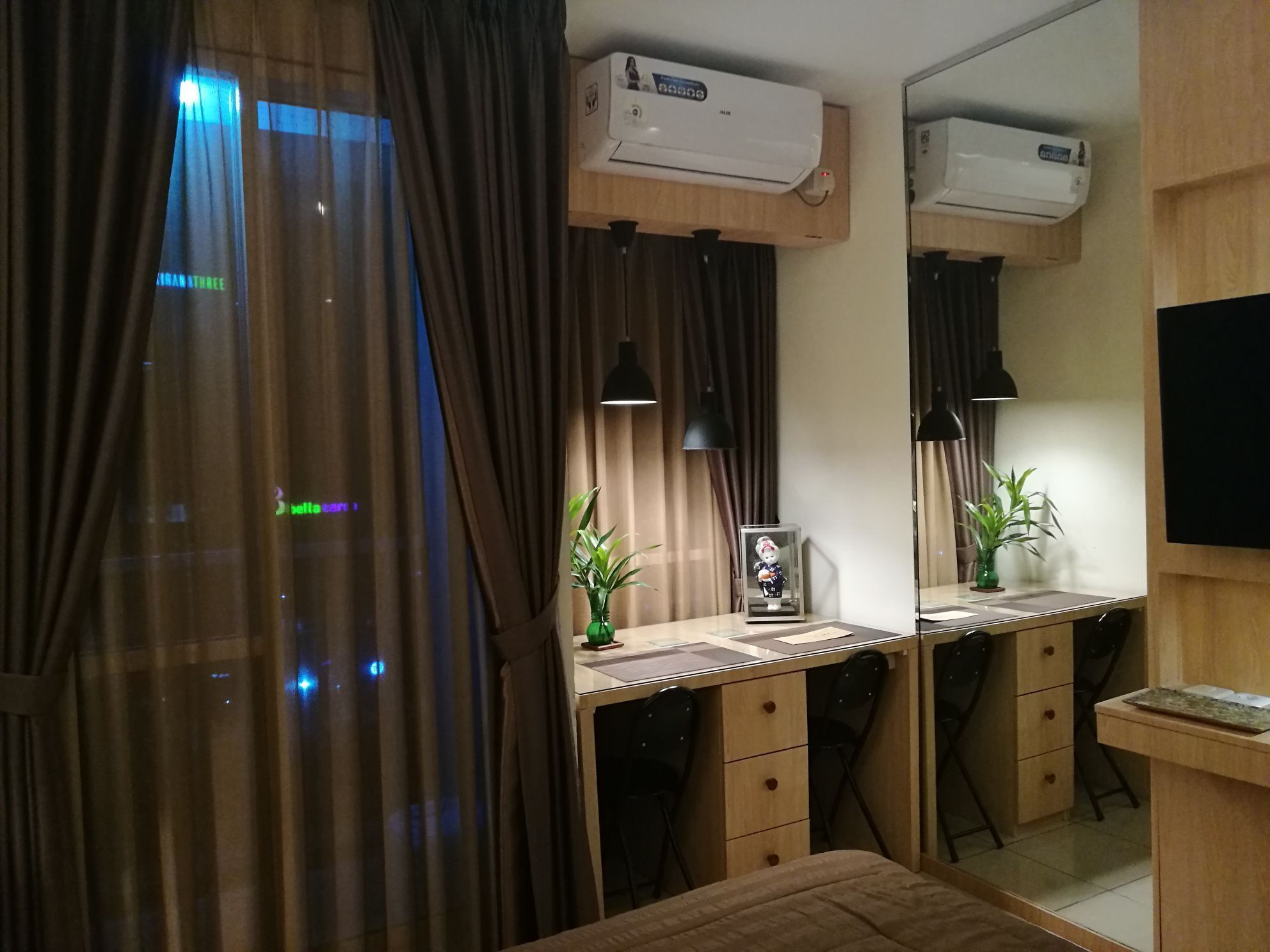 Une chambre moderne avec un bureau en bois, deux chaises, un lit et un appareil de climatisation.