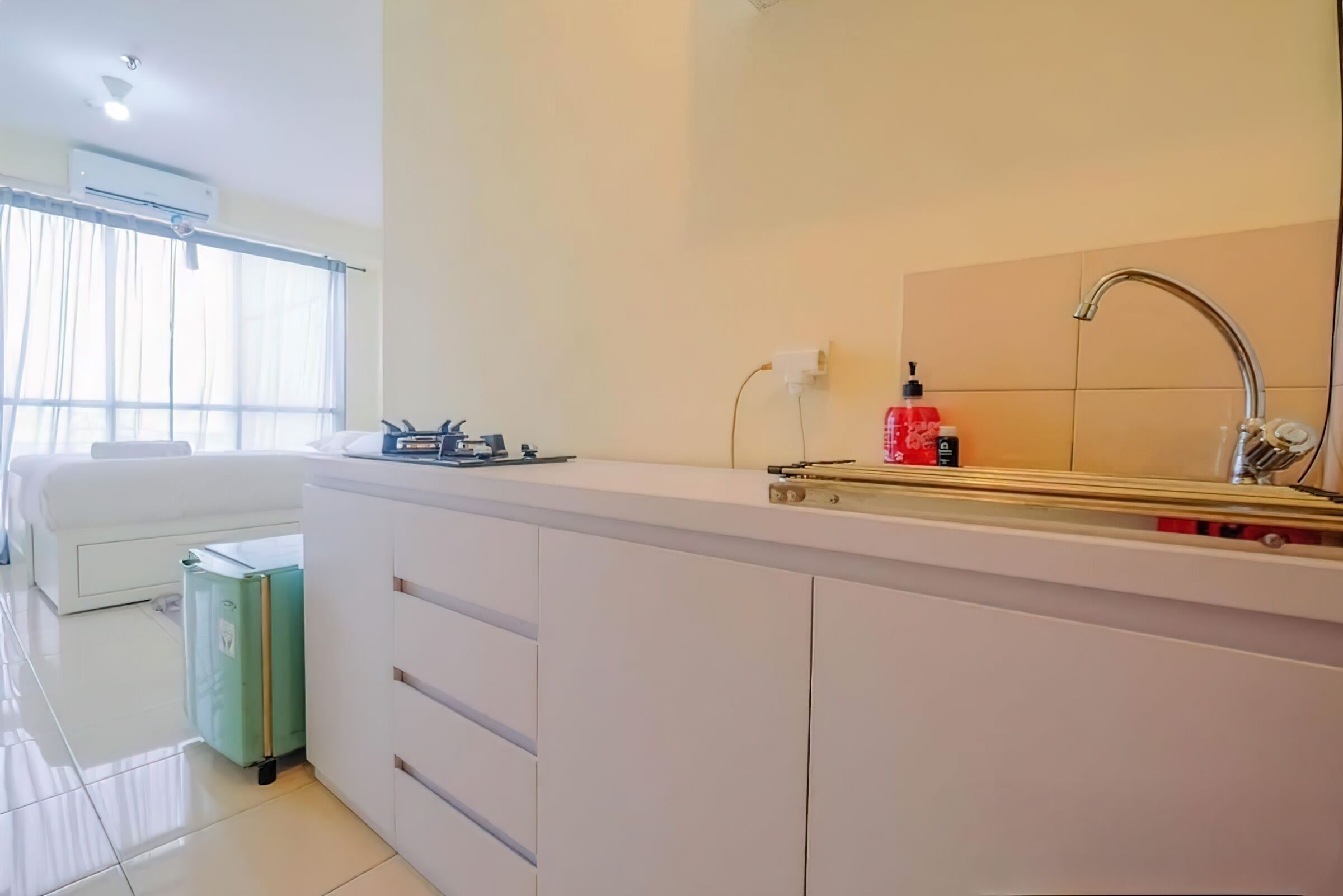 Una cucina moderna con un piano di lavoro bianco, un lavello e una finestra con tende leggere.