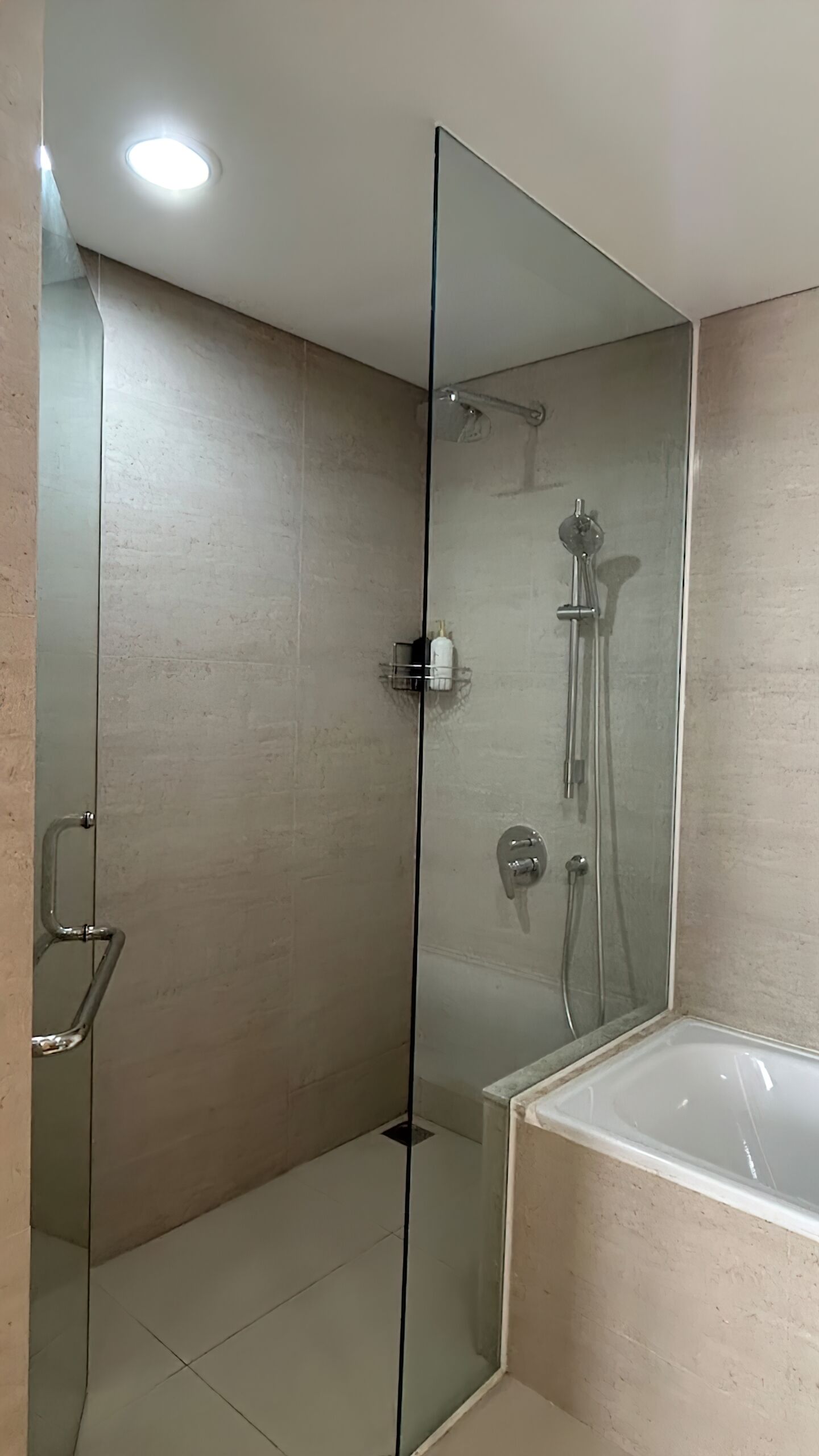 A modern bathroom with a glass shower enclosure, a bathtub, and a toilet.