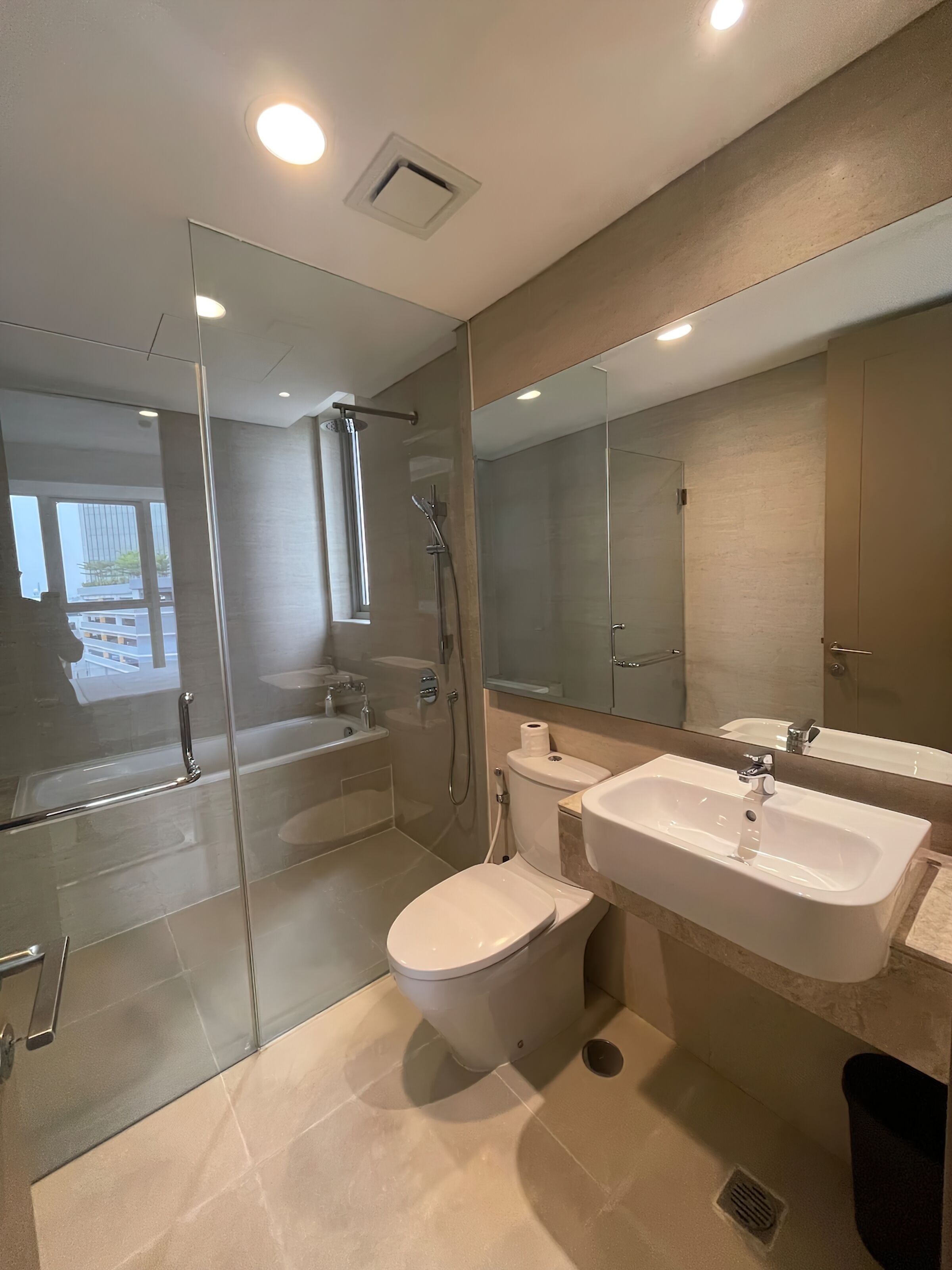 Een moderne badkamer met een douchecabine van glas, een toilet en een wastafel.