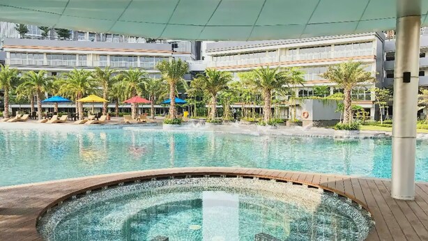 A swimming pool with a hot tub in the center, surrounded by lounge chairs and umbrellas. - Seaview GoldCoast Residence in Jakarta (Jakarta)
