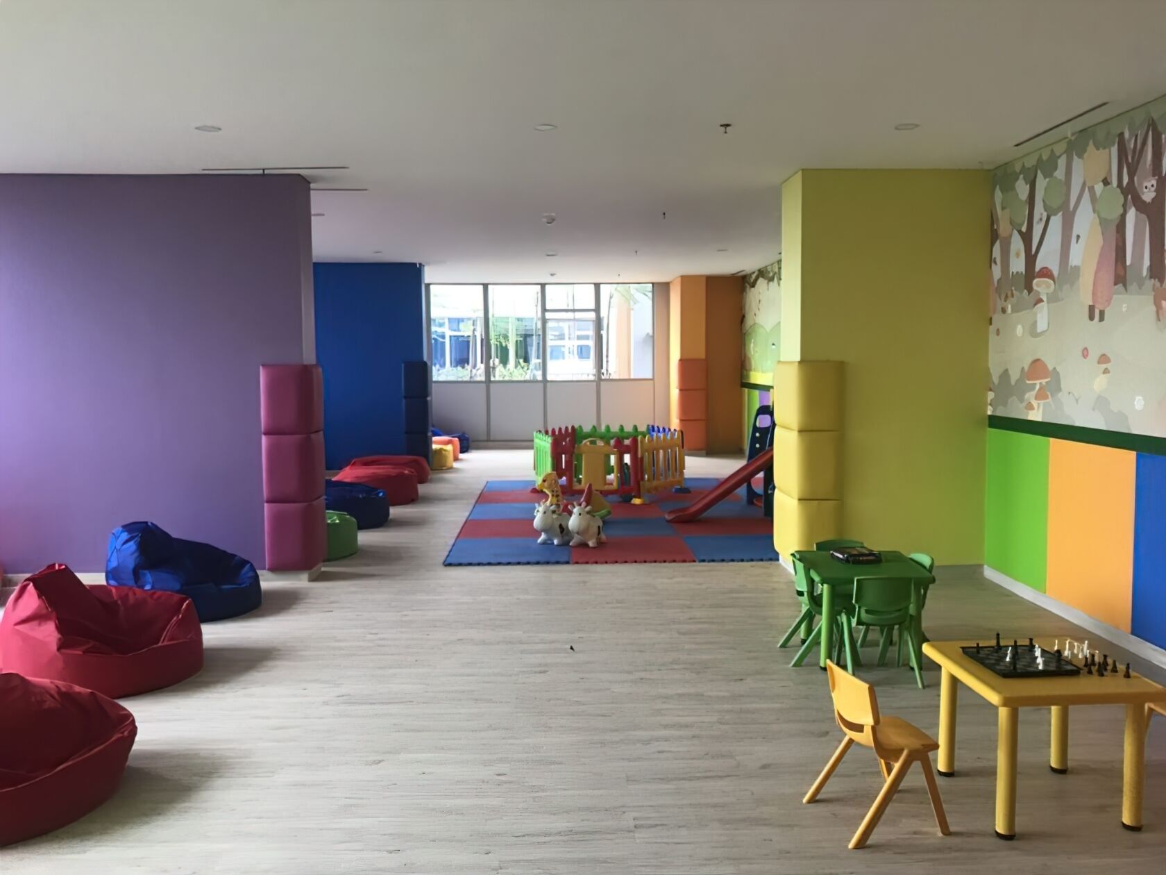 A modern children's play area with colorful bean bags, a slide, and a chess table.