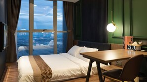 A hotel room with a large window, a bed, a desk, and a clock. - Seaview GoldCoast Residence in Jakarta (Jakarta)
