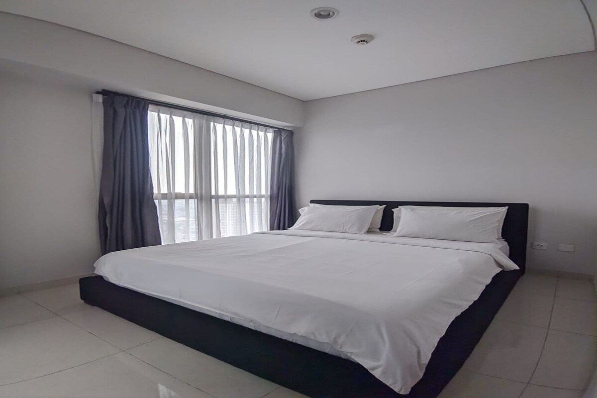 A bedroom with a bed, a window with curtains, and a ceiling light.