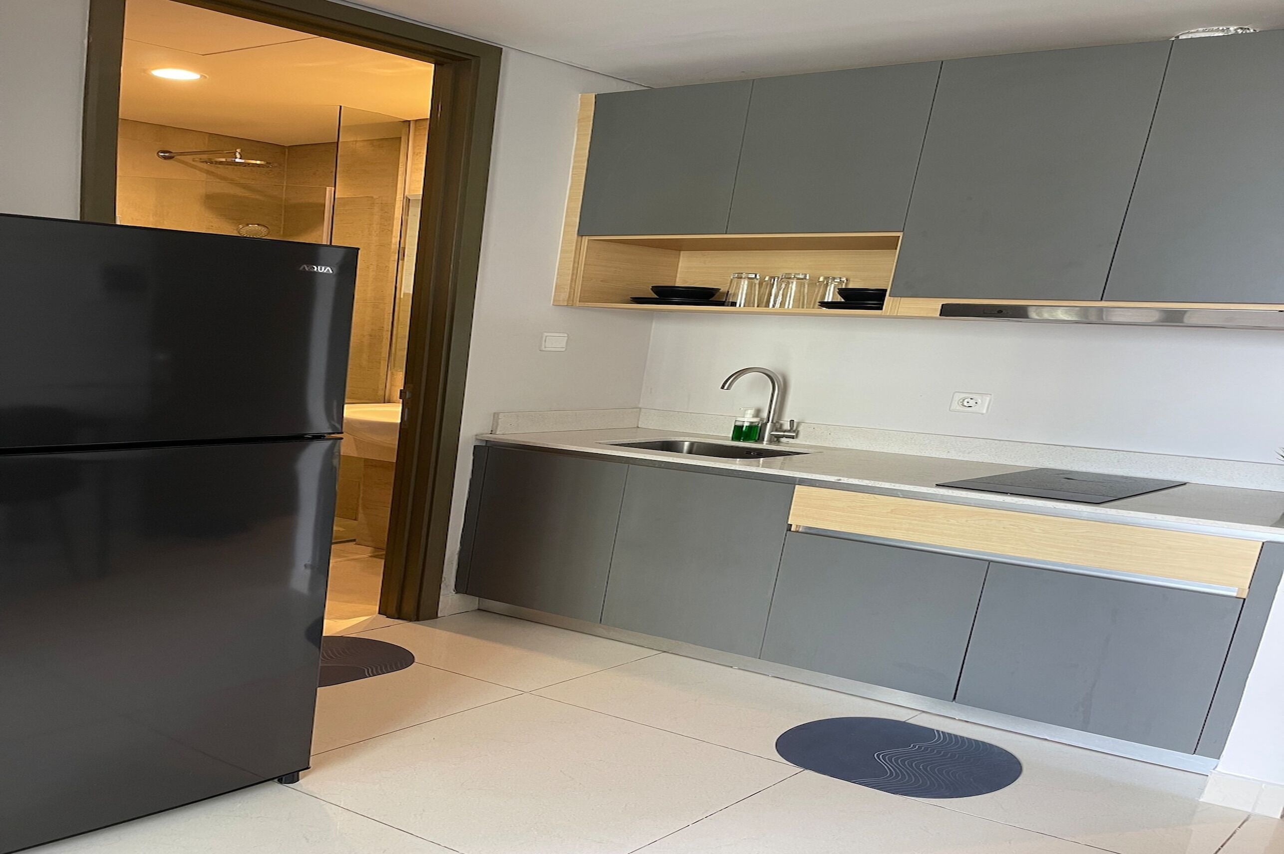 A modern kitchen with grey cabinets, a black refrigerator, a wooden countertop, and a built-in sink.