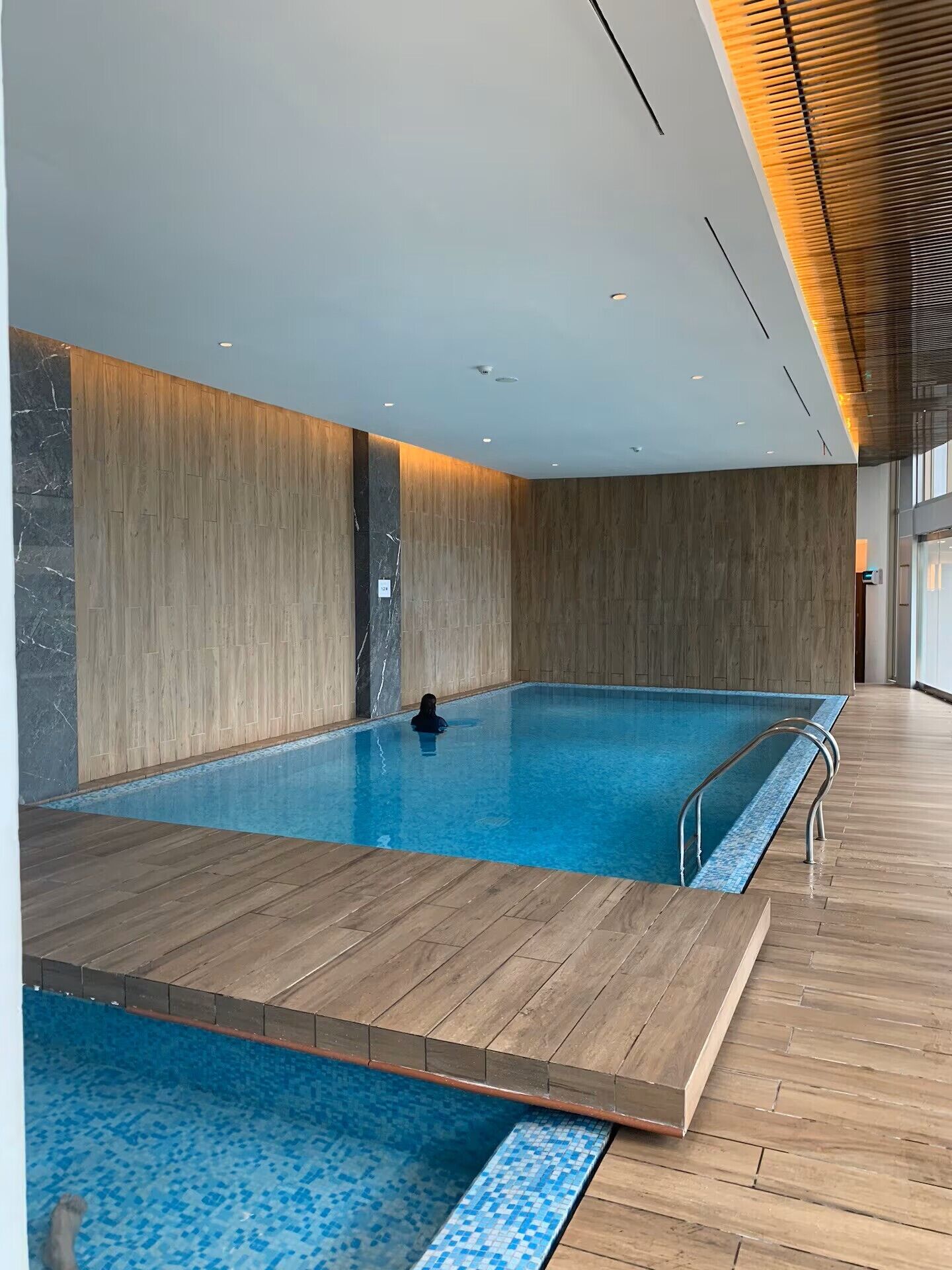 An indoor swimming pool with wooden walls and a tiled floor.