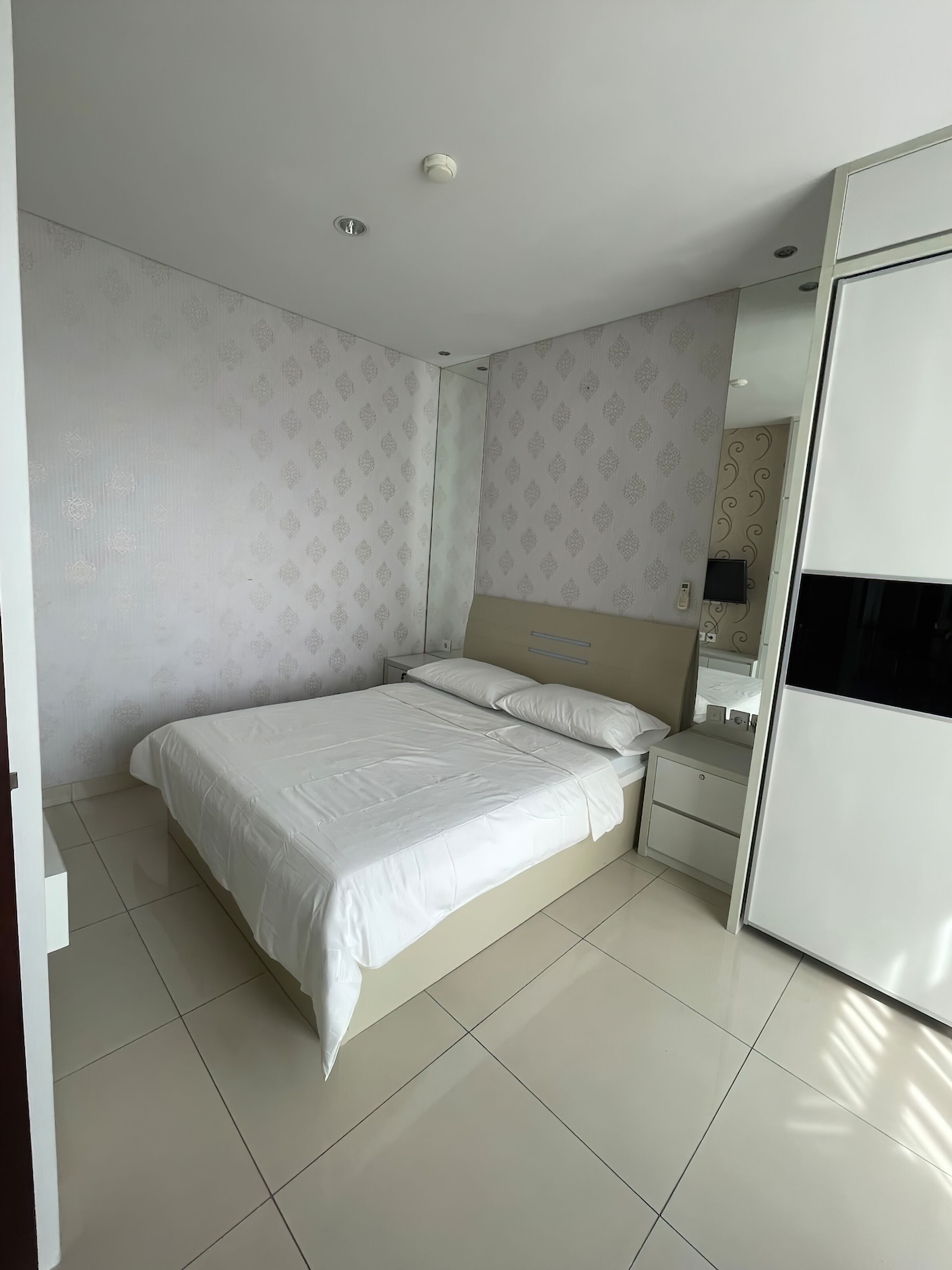 Un dormitorio con una cama, una mesita de noche, un aparador y un espejo.