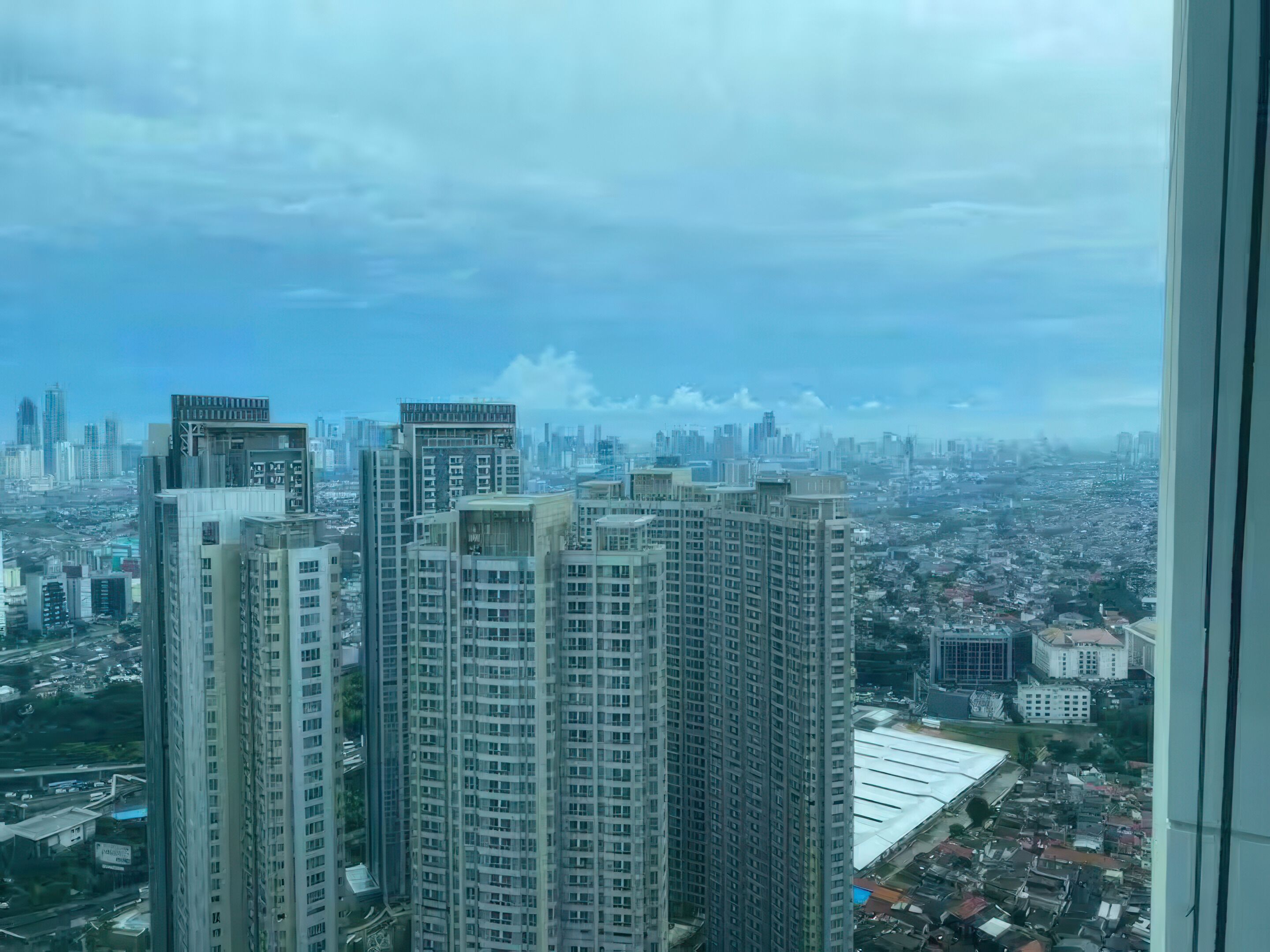 Un immeuble de grande hauteur, doté de nombreux étages, de grandes fenêtres et offrant une vue sur un paysage urbain composé de différents bâtiments et infrastructures.
