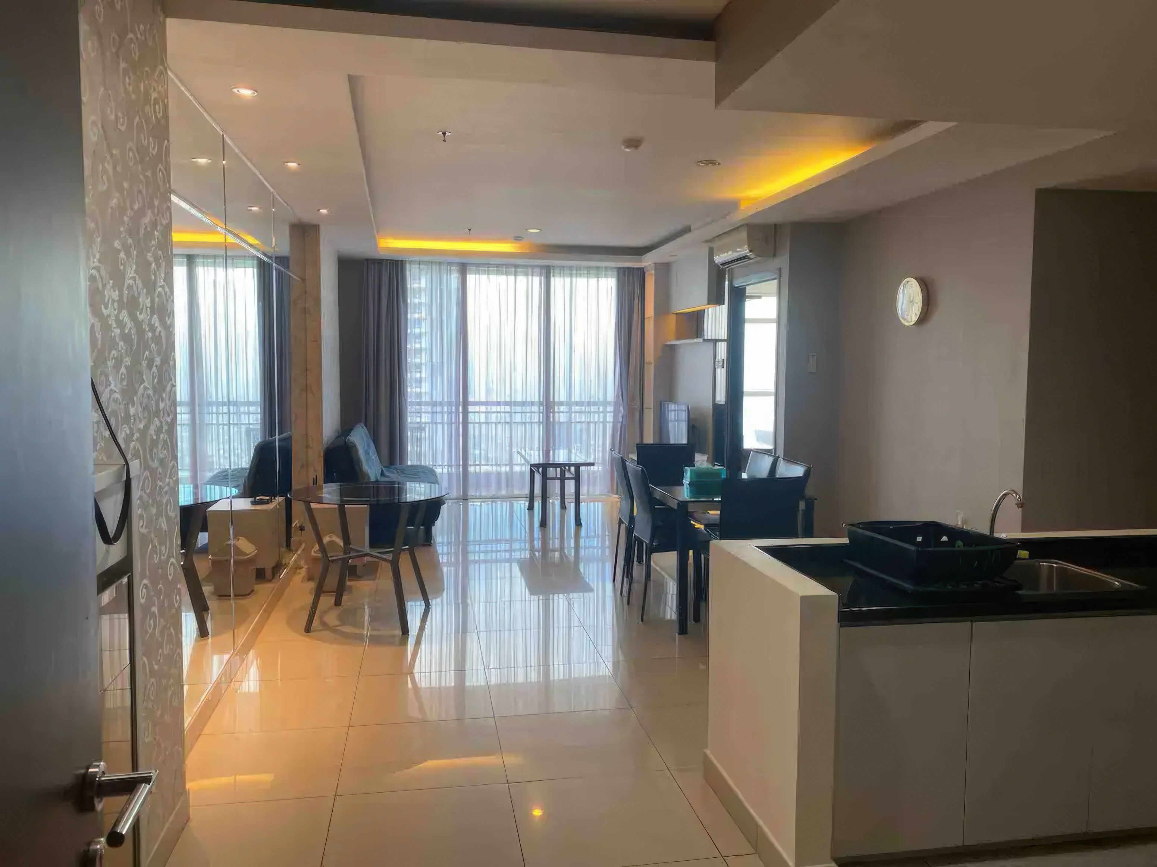 Une chambre d’hôtel moderne comprenant un coin repas, un canapé, une petite table et un coin cuisine équipé d’un évier et de placards.