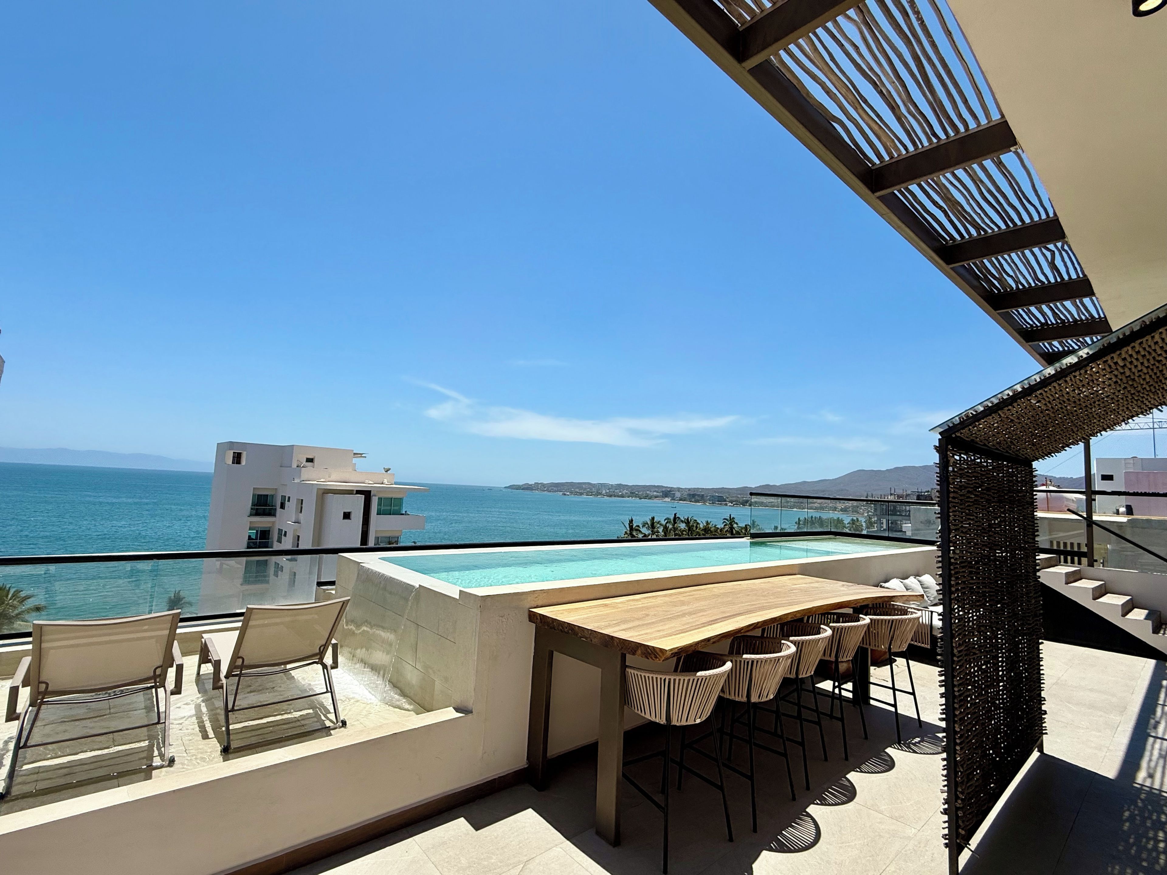An outdoor terrace with a pool, seating, and a view of the sea.