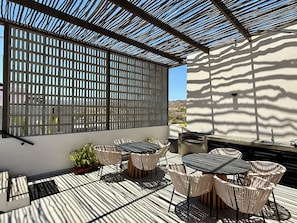 Une terrasse extérieure avec une table et des chaises, un barbecue et une vue sur le paysage.