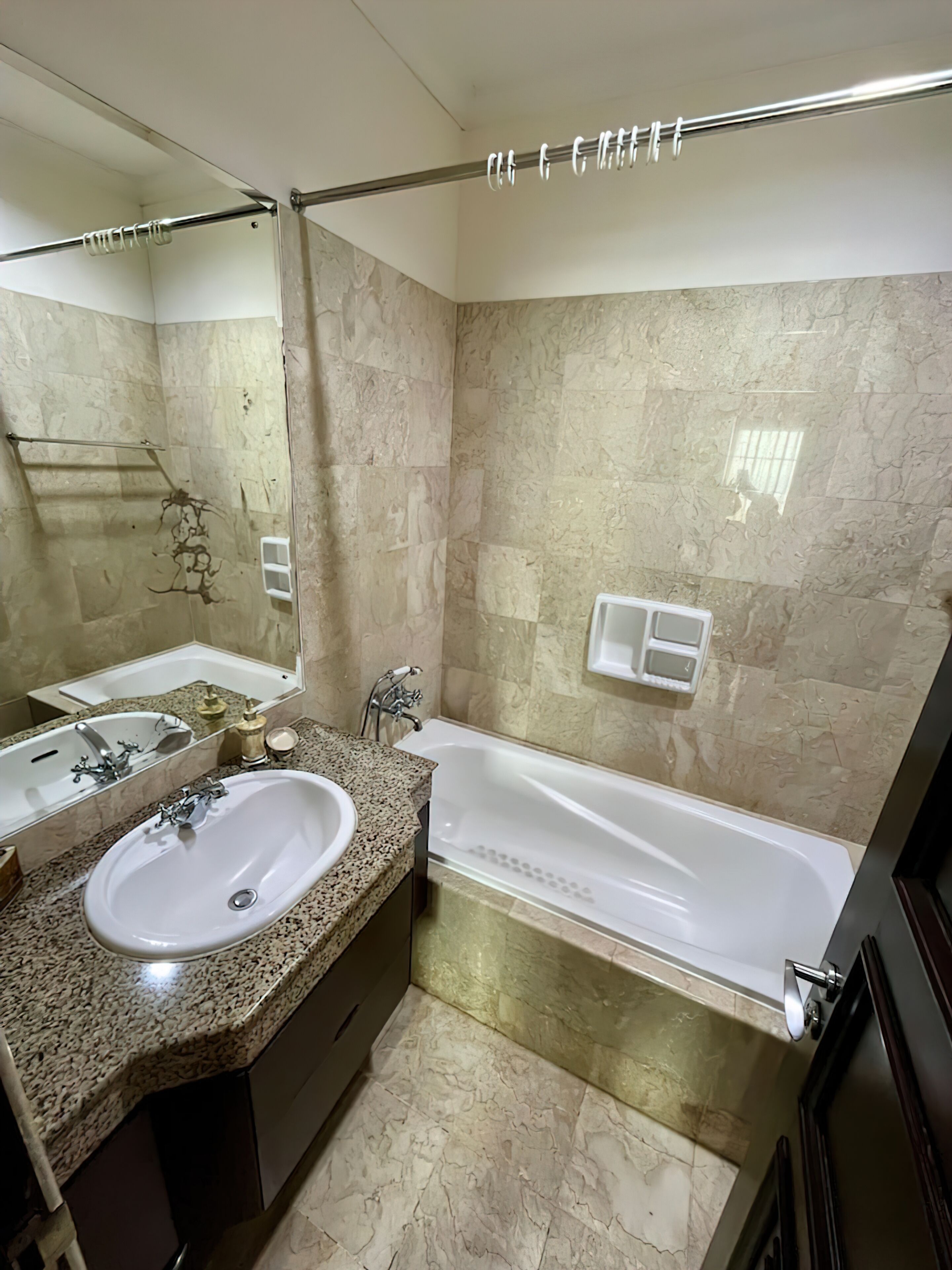 A bathroom with a sink, mirror, and bathtub.