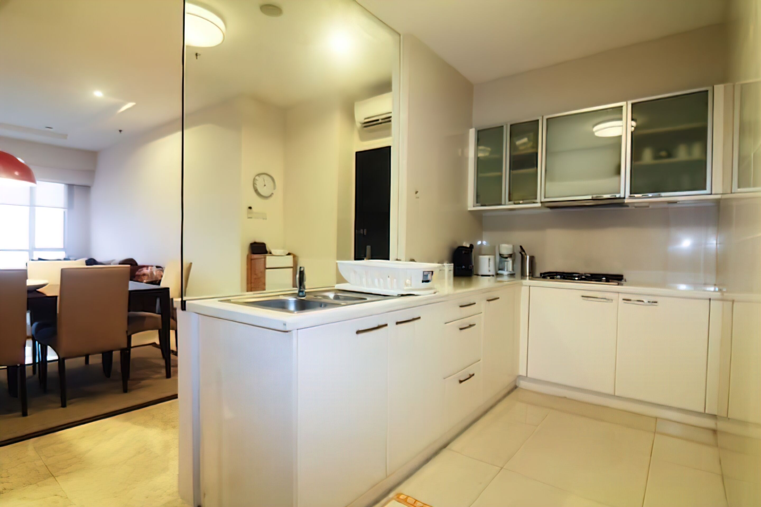 Una cucina moderna con mobili bianchi, lavello incassato e zona pranzo con sedie e tavolo.