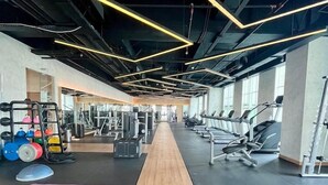 A gym with exercise equipment, a wooden running track, and a row of treadmills. - Somerset Berlian Suites Jakarta (Jakarta)