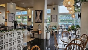 A modern restaurant with a bar area, wooden chairs, and hanging lights. - Somerset Berlian Suites Jakarta (Jakarta)