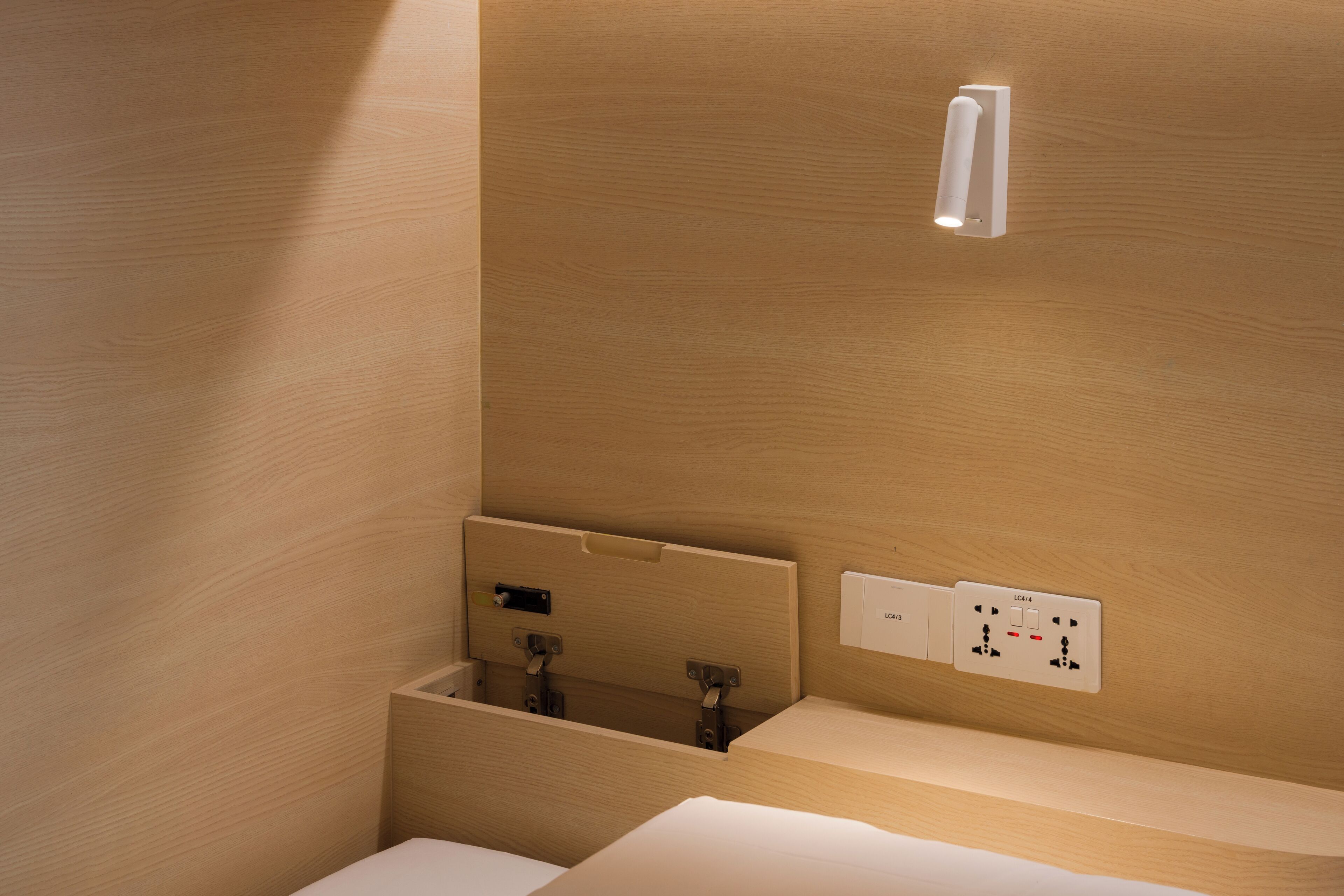 Een houten badkamer met een ingebouwd wastafelmeubel, een spiegel en een wandlamp.