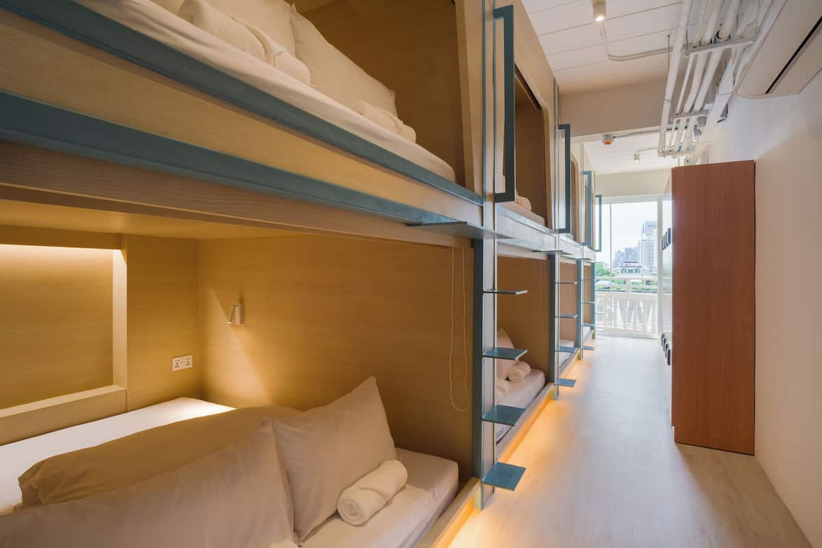 Ein modernes Hotelzimmer mit Stockbetten, einer Schlafcouch, einem Nachttisch und Blick auf die Stadt.