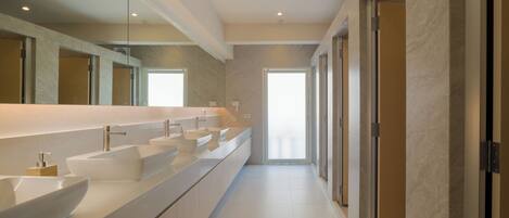 A modern bathroom with a long vanity, multiple sinks, and a large mirror.