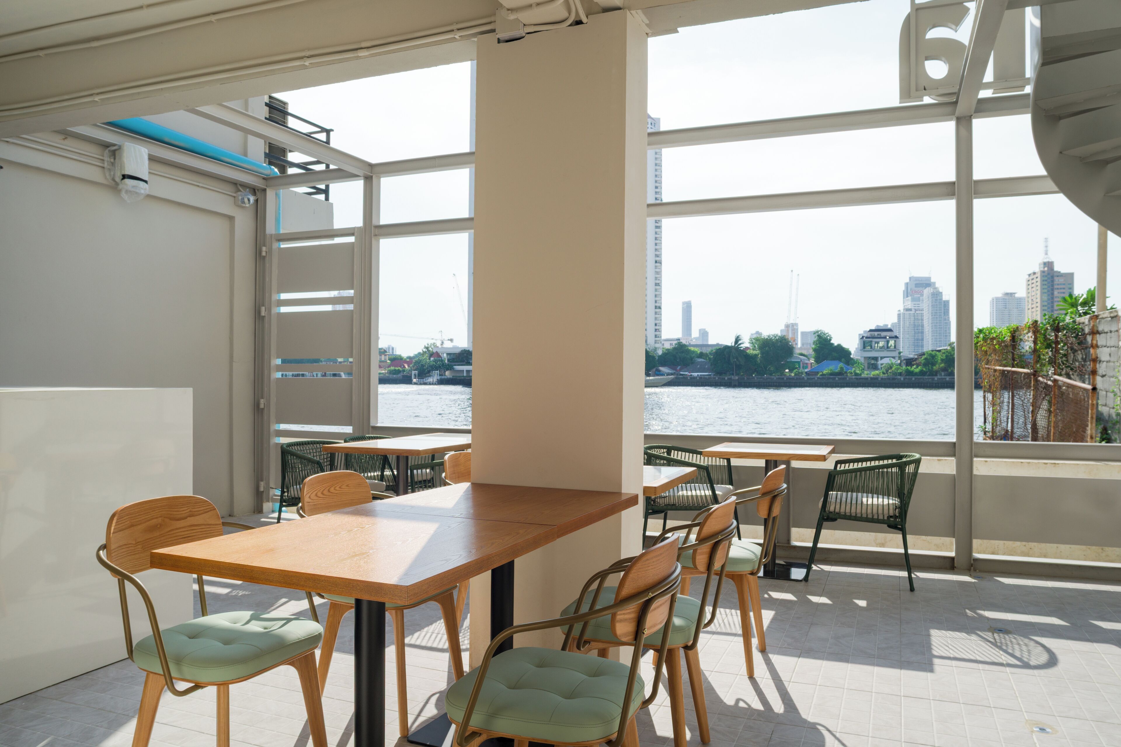 Un comedor moderno con una mesa grande y sillas, ventanas amplias que ofrecen vistas a un horizonte urbano y una masa de agua.