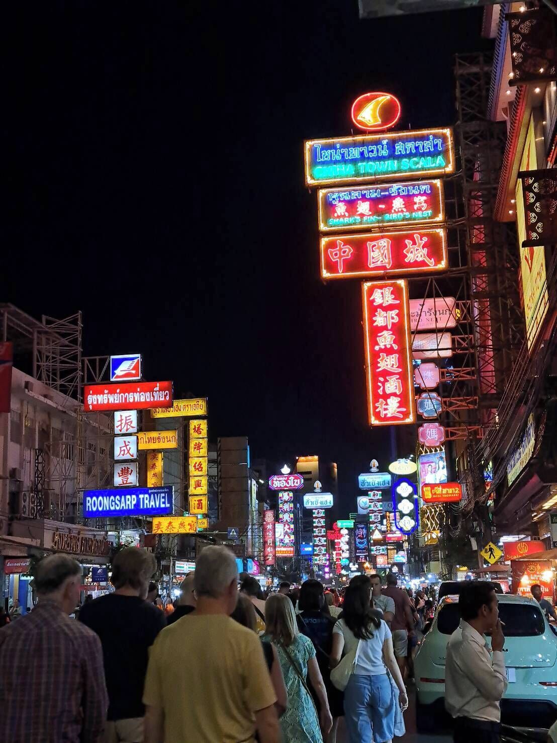 A busy street at night with numerous illuminated signs in a foreign language, indicating a vibrant urban area.