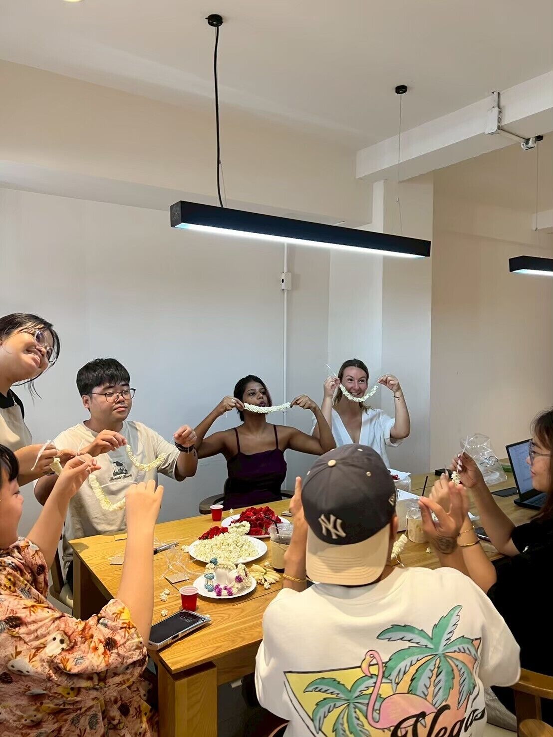 Un grupo de personas sentadas alrededor de una mesa en una habitación con diseño moderno, que destaca una mesa de madera y una estética sencilla y depurada.