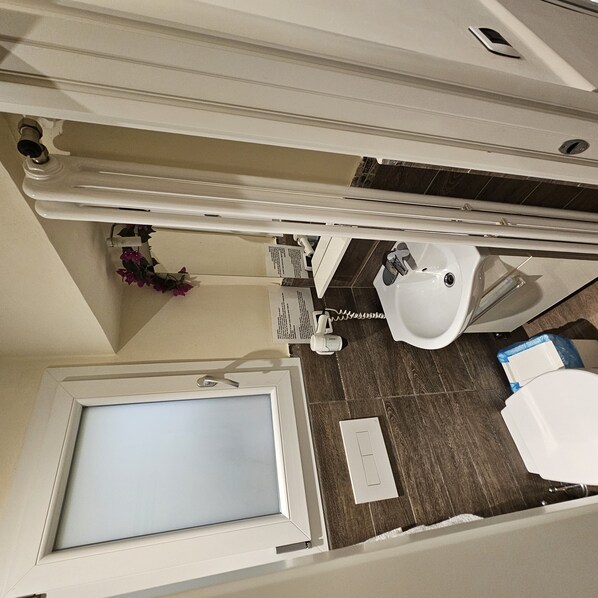 A compact bathroom with a toilet, sink, and a shower area. - Naples Single Room with Private Exterior Bathroom (Firenze)