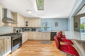 A modern kitchen with a central island, stainless steel appliances, and a view of a lake.