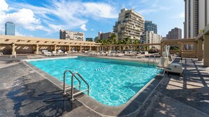 Una piscina con sillones de descanso y vistas a edificios altos.