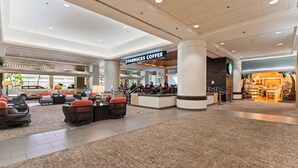 Un vestíbulo amplio con una cafetería Starbucks, zonas de estar y una escalera que conduce a los pisos superiores.
