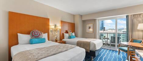 A hotel room with two beds, a balcony with a view, and a small dining area.