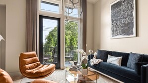 Una sala de estar moderna con un sillón de cuero, un sofá azul oscuro y una mesa de centro de vidrio.