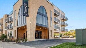 Un hotel moderno con un llamativo letrero 'NEO', grandes ventanales en arco y una entrada cubierta.