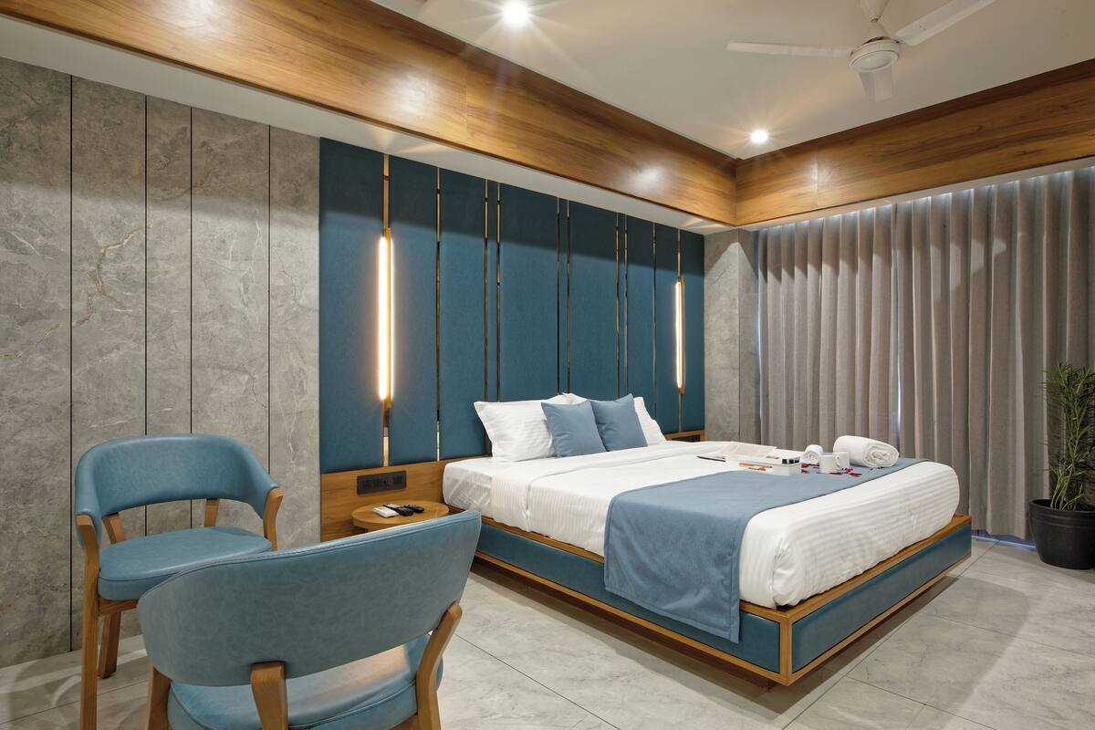 A modern bedroom with a large bed, a wooden ceiling, and a potted plant.