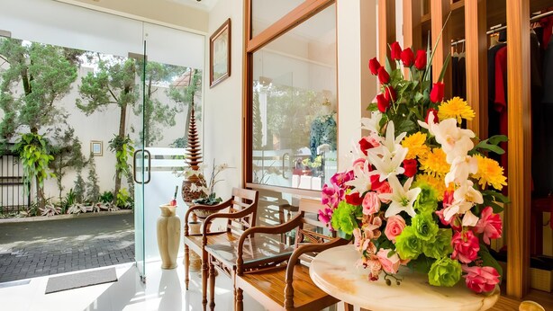 A hotel lobby with a seating area, a large window, and a floral arrangement. - Pilatus Hotel Bandung (Bandung)