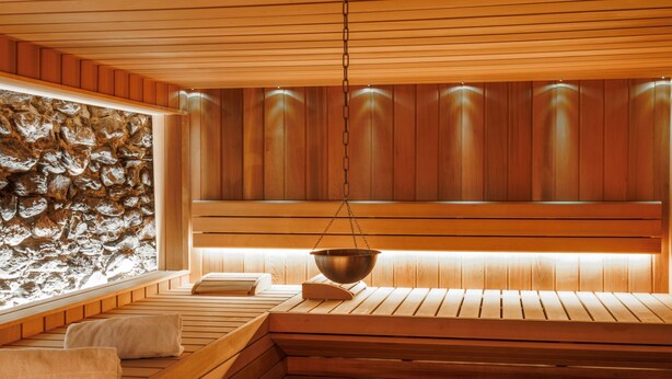 A sauna with wooden benches, a stone wall, and a hanging bowl. - Victoria by Interhome (Vercorin)