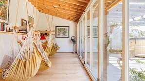 A room with wooden floors, a ceiling with exposed beams, and a row of macramé hammocks. - Victoria by Interhome (Vercorin)
