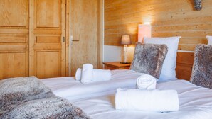 A hotel room with wooden panel walls, a bed with white linens, a nightstand with a lamp, and a deer head decoration. - Victoria by Interhome (Vercorin)