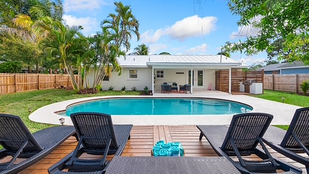 A backyard with a swimming pool, lounge chairs, and a wooden deck.