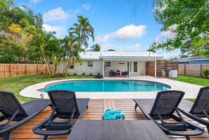 Un jardin avec une piscine, des chaises longues et une terrasse en bois.