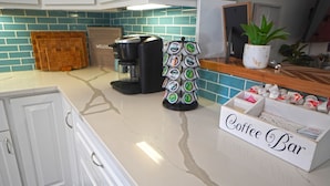 A kitchen with a coffee maker, a coffee bar sign, and a potted plant.